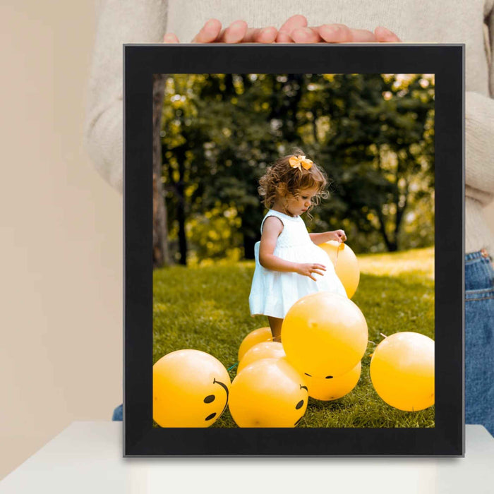 a person holding a picture of a child surrounded by balloons