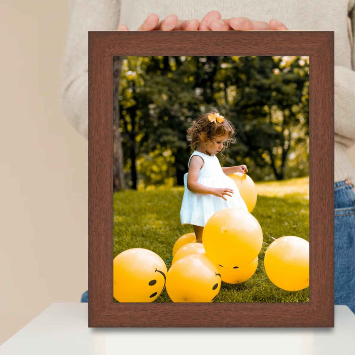 a person holding a picture frame with a picture of a little girl surrounded by balloons