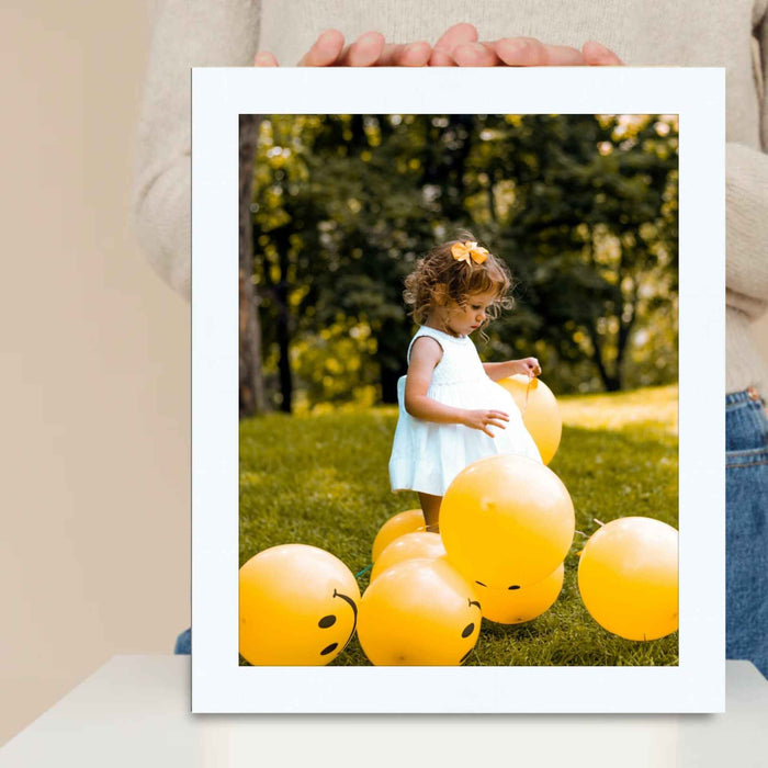 a person holding up a picture of a child surrounded by balloons