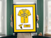 a person holding a framed picture of a baseball uniform